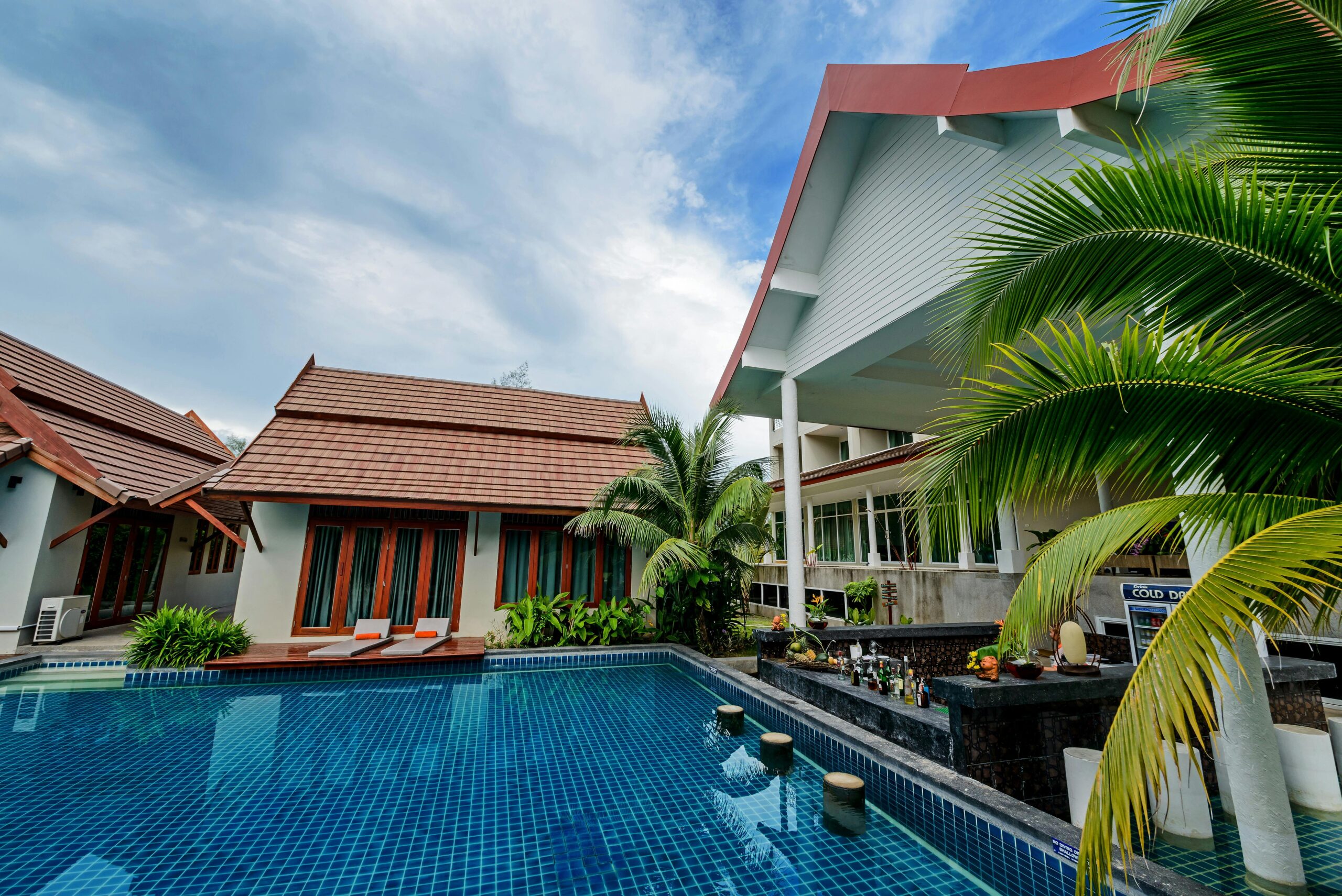 Serene resort pool with modern architecture and lush palm trees under a clear sky.